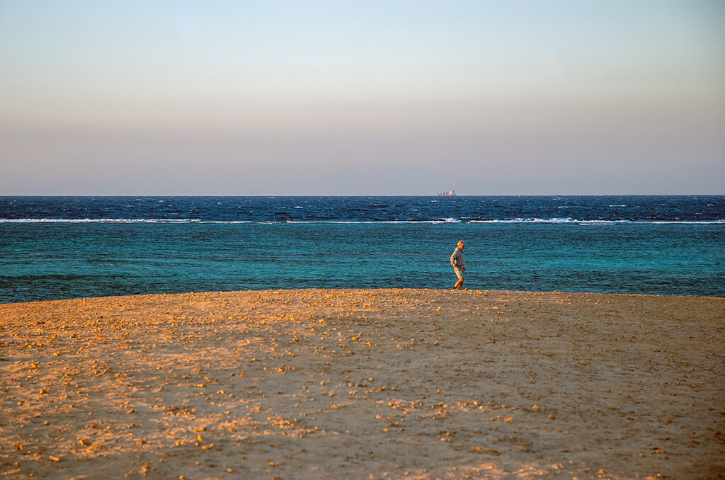 a person on the sandy island next to the blue sea